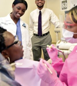 Clifton Bush observes Dr. Shayla Browner (DMD ‘15) and hygienist Ashley Scott (BS Dental Hygiene ‘12). Photo by Todd Stone.