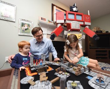 Charlotte, Wes and Bella Kisting role-play with a homemade Dungeons & Dragons game table, as Optimus Prime looks on.