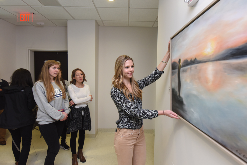 Gabrielle Going adjusts the painting, "In Memory of Dr. Konchady."