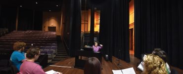 Associate music director and voice coach Pam McCorkle works with the cast on the stage of the Maxwell Theatre.