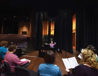 Associate music director and voice coach Pam McCorkle works with the cast on the stage of the Maxwell Theatre.