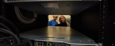 Two women looking through window in server farm