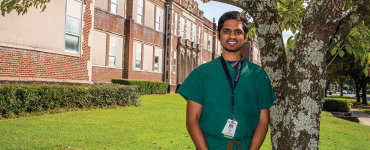 man smiling in front of building