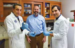 Three men standing in a lab smiling