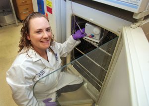 Woman crouched in lab smiling at camera