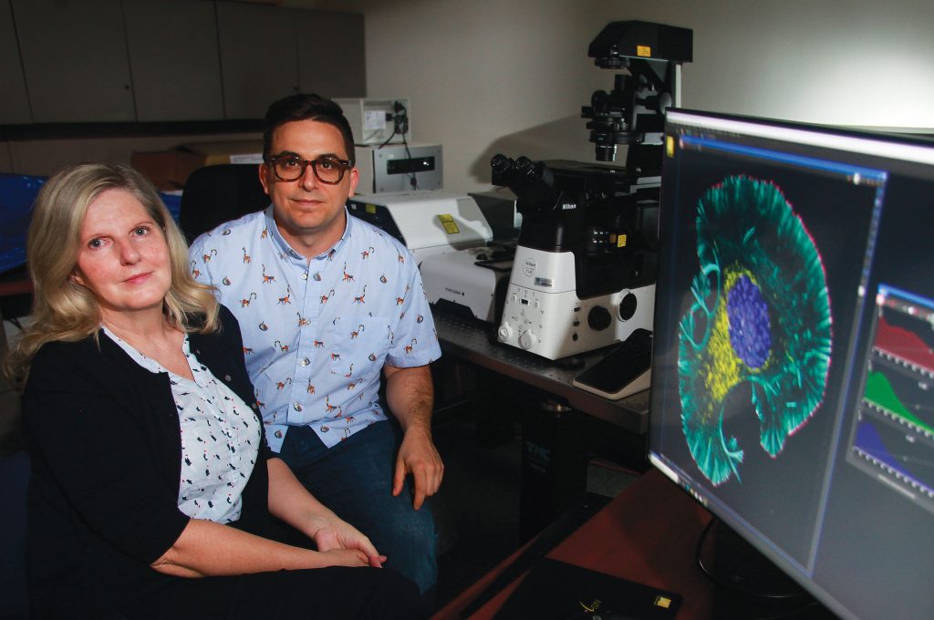 man and woman sitting in lab smiling at camera