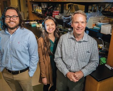 three people standing in a lab smiling