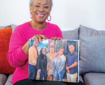 woman smiling at camera holding picture of her five children.