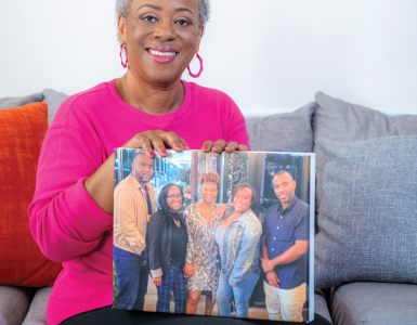 woman smiling at camera holding picture of her five children.