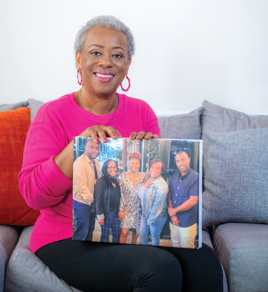 woman smiling at camera holding picture of her five children.