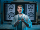 man stands in lab posing for camera in front of x-rays of a skull