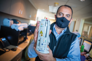 doctor holding instrument posing for camera in lab.