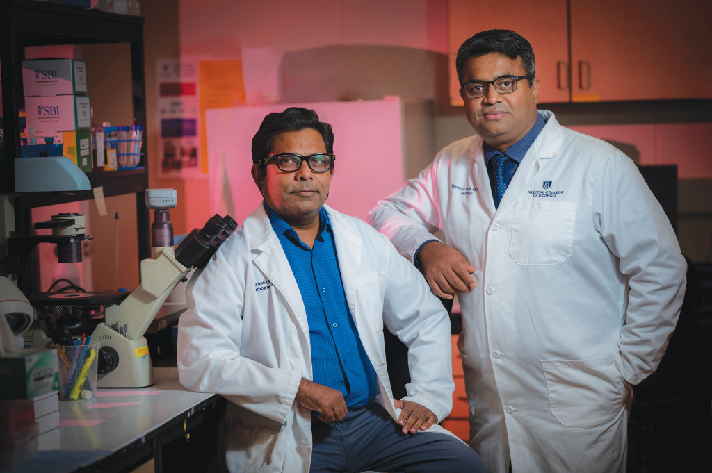 Two men in a lab pose for camera