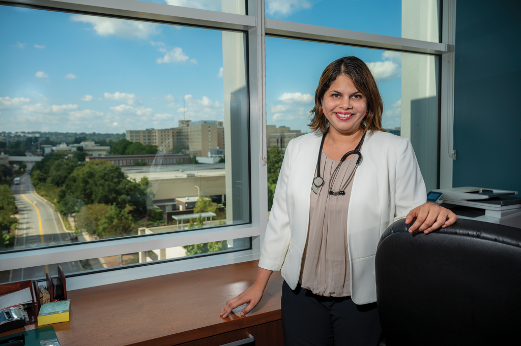 woman standing in front of building window smiles at camera