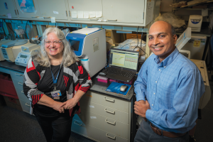 woman and man sitting in lab smiling at camera.