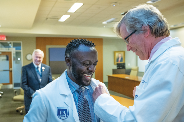 man adds a pin to another man's white coat
