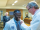 man adds a pin to another man's white coat