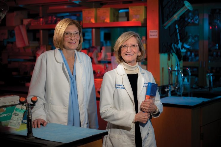 two female scientists smile into camera