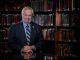 President Brooks A. Keel, PhD poses for camera in front of shelves of books.